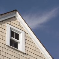 House peak with tan wooden siding and a white wood frame window against a beautiful blue sky.; Shutterstock ID 491708395